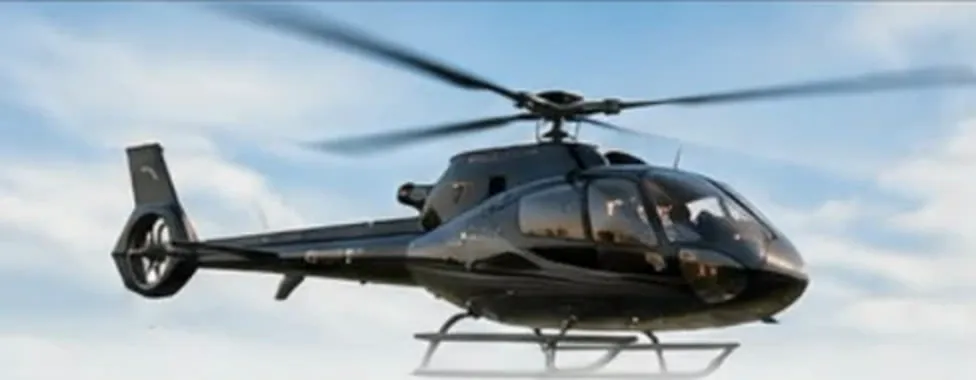 מסוק Airbus H130 שחור בטיסה בשמיים כחולים